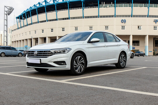 January 31, 2021, Seoul, South Korea - A white Volkswagen Jetta sedan parked in a lot in front of a baseball stadium.