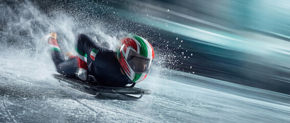 Skeleton athlete with an Italian helmet speeding down an ice track. Dynamic winter sport action shot with high-speed motion blur and flying ice spray for the 2026 games concept.
