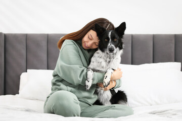Fototapeta premium Woman with her cute Border Collie dog on bed at home