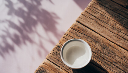 木製コースターに置かれた白いお猪口と桜の影