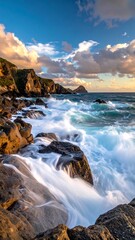 Fototapeta premium Waves crash against a rocky shore during golden hour under a blue and cloudy sky, creating a dynamic landscape
