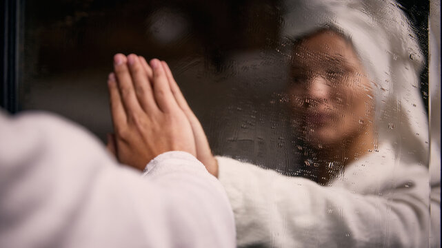 Woman touching foggy mirror after shower in bathroom. Concept of intimate self care, wellness atmosphere, skincare lifestyle, emotional reflection and calm solitude.