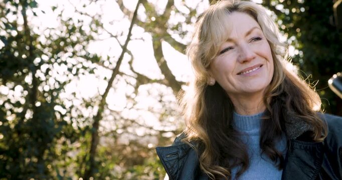 Attractive happy middle aged woman in her forties outside smiling and laughing in golden winter sunshine