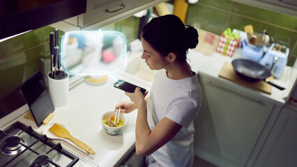 Smartphone with intelligent AI assistant interface assisting cooking process. Concept of artificial intelligence communication, smart kitchen systems, contextual recipe support, home technology.