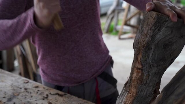 Artisan hand carving 150 year old chestnut wood with adze vertical