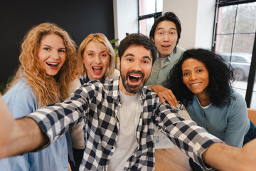 Diverse group of multinational friends taking fun selfie group in office looking at camera