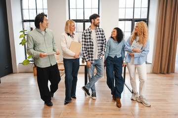Fototapeta premium Diverse group of smiling confident business team walking together in modern office