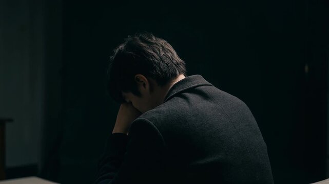 Emotional young man in dark setting reflecting on life, capturing moments of introspection and vulnerability
