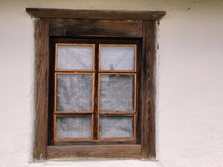 Vintage wooden window with simple frame set in a white plastered wall of a traditional countryside home.