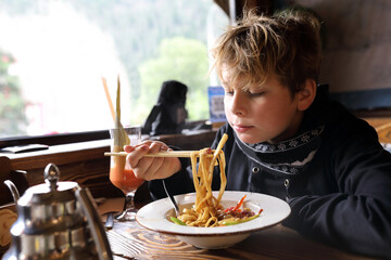 Boy eating chinese noodle with chopstick