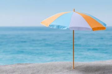 a beach umbrella with striped orange and blue colors on the sand by the sea, a summer vacation concept.