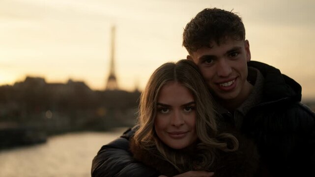 A young couple embraces in Paris France with the Eiffel Tower visible in the background at sunset The lovers are hugging showcasing affection and togetherness against the Parisian cityscape The warm g