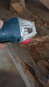 Artisan sanding 150 year old chestnut wood with angle grinder vertical