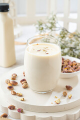 A tasty hazelnut milkshake in a glass on a white plate with nuts