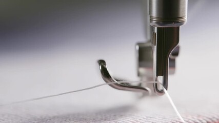 Sewing machine needle in action: closeup on fabric with thread movement
