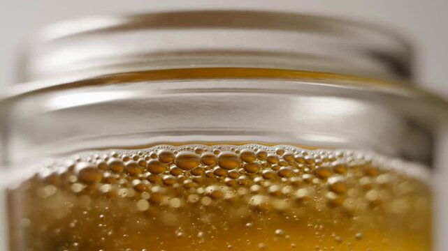 Closeup of rising bubbles in amber liquid within a glass jar