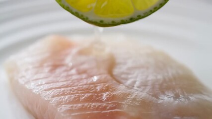 Fresh lime juice dripping over raw fish fillet for culinary preparation and flavor enhancement