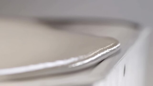 Metallic liquid flowing over edge in high resolution closeup sequence