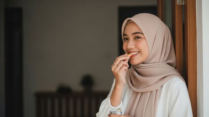 Woman in hijab eating a cookie by a doorway.