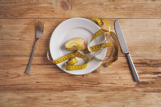Diet - A plate with only one apple slice and cutlery.