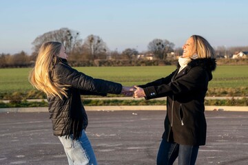 Obraz premium Two women having fun spinning together outdoors, joyful friendship moment. Mother and daughter having fun spinning together outdoors, joyful family moment