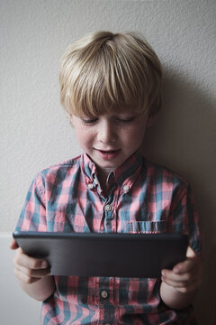 Boy Happily Looking at Tablet Device