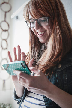 Woman Smiling While Holding and Tapping Phone