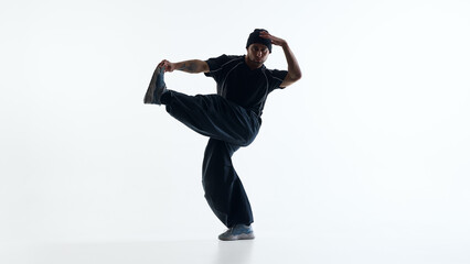 Breakdance dancer performing high kick balance move isolated on white studio background. Concept of sports branding, urban fashion promotion, youth marketing visuals and dynamic web design content.