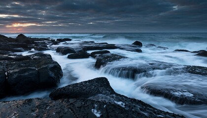 Serene ocean waves crashing against dark rocks at dusk.