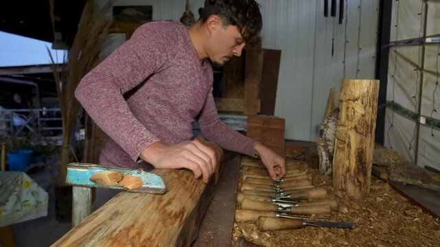 Side view of artisan selecting chisel from workshop tools