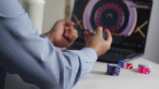 Excited overjoyed man at computer desk holding online casino poker chips, jetons, winner feeling euphoric with bet gambling victory, looks at screen celebrates fantastic news, received best prize
