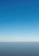 Fototapeta premium A peaceful, expansive, wide-angle view of a seamless horizon line where the vast blue sky meets a soft, empty, featureless ground plane ,wide ,subtle ,horizontal