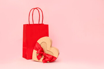 A holiday backdrop with a heart-shaped cardboard box with a bow, gift bags on a pink background. Perfect for holiday shopping, Mother's Day, weddings, and Valentine's Day.