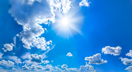Beautiful blue sky background with sun rays and cumulus clouds. Large and small vapor structures are arranged in a chain, flowing smoothly along the horizon. Wide website banner. Positive copy space.