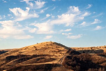 Naklejka premium A picturesque view of a gently rolling golden hill, lit by the sun, under a bright blue sky with light cirrus clouds. A beautiful rural landscape in warm tones, conveying the spaciousness and tranquil