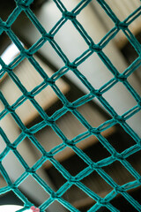 Fototapeta premium Heavy duty Knotted Netting Yellow, green and blue colors. A Rope Net is Attached To the Concrete Wall and is Obliquely. Yellow Rope Climbing Net. 