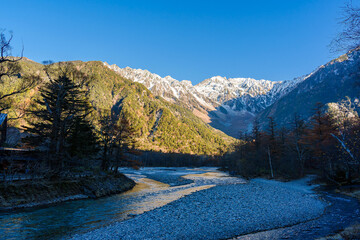 Beautiful mountains and the Azusa River of Kamikochi National Park glowing in the morning sunlight during autumn in Nagano, Japan.