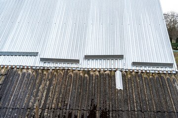 Close-up view of a corrugated metal roof with contrasting textures of aged metal and a rusty surface beneath. Ideal for construction, architecture, or design topics.