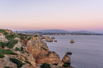 Cliffs and rocks near Praia do Camilo with mountains in the background during sunset in Algvare region of Portugal in Lagos