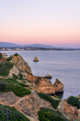 Cliffs and rocks near Praia do Camilo with mountains in the background during sunset in Algvare region of Portugal in Lagos