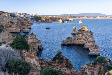 Cliffs and rocks near Praia do Camilo with mountains in the background during sunset in Algvare region of Portugal in Lagos