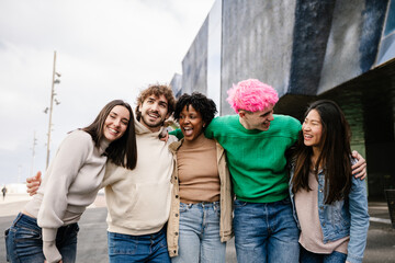 Young diverse group of friends walking together outdoors. Happy students enjoying time outside while talking and bonding. Youth community and friendship concept.