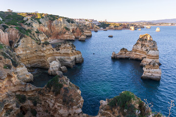 Cliffs and rocks near Praia do Camilo with mountains in the background during sunset in Algvare region of Portugal in Lagos