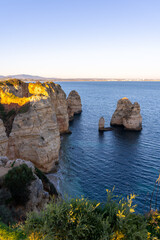 Jagged limestone cliffs rising dramatically from turquoise waters at Ponta da Piedade during sunset in Lagos, Portugal with vast Atlantic ocean in the background
