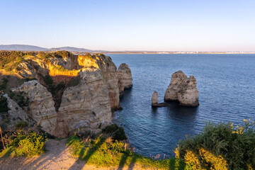 Jagged limestone cliffs rising dramatically from turquoise waters at Ponta da Piedade during sunset in Lagos, Portugal with vast Atlantic ocean in the background