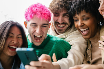 Multicultural group of university students are relaxing outdoors, scrolling through content on phones. Youth community and technology lifestyle concept.