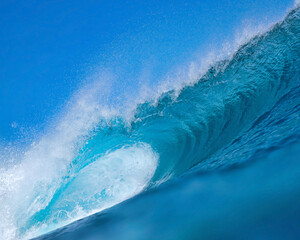Massive blue ocean wave curling, bright turquoise barrel breaking with foamy crest and spray, sunlight