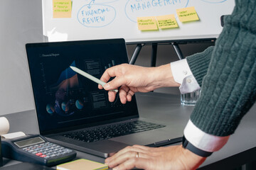 Business financial analysis on laptop screen with hand pointing data chart