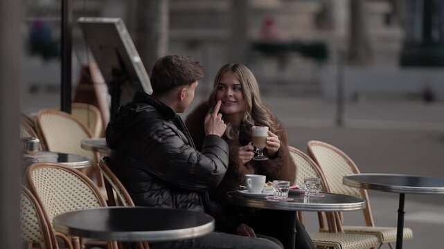 A romantic couple shares a drink at an outdoor in Paris France The man playfully touches the woman's lip with his finger as she holds a latte The scene captures a moment of love and affection in a Par