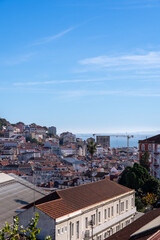 Fototapeta premium A classic wrought iron fence and street lamp at a Lisbon miradouro, framing the city and the Tagus river in the distance.